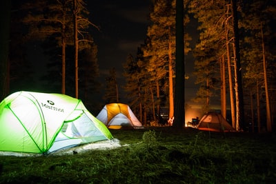 营火旁的森林里有三个带灯的圆顶帐篷